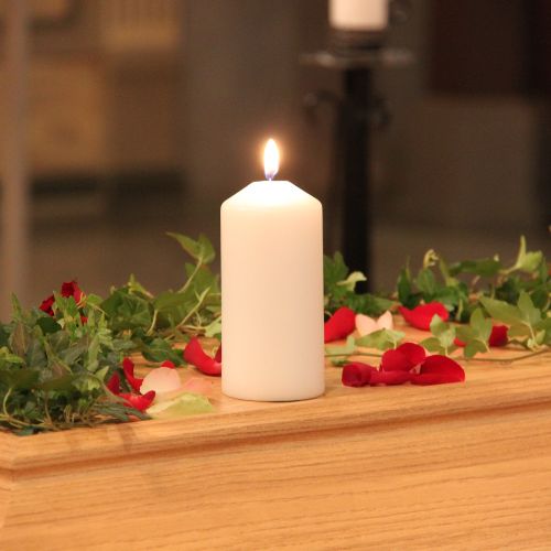 A lit candle on a coffin with roses and ivy